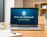 Ein Laptop zeigt "Drive-by-Downloads ABWEHREN". Das ist eine Methode, um schädliche Software unbemerkt zu installieren.