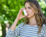 Frau mit Inhalator im Freien. Bei Asthma kann die richtige Dosierung von Prednisolon Tabletten wichtig sein.