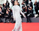 Isabelle Huppert, éblouissante dans sa robe argentée à franges, foule le tapis rouge de la mostra de Venise, sous le regard des photographes.