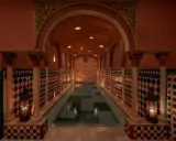 Ein prachtvoller Hammam in Granada mit einem langen Pool, umgeben von kunstvollen Kacheln und Säulen, beleuchtet von Kerzen.