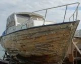Bateau en bois sur cale, prêt à être restauré. Il faudra le nettoyer avant de naviguer sans antifouling.