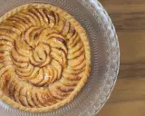 Tarte aux pommes dorée sur pâte feuilletée, disposée en spirale sur un plat en verre gravé. Un délice croustillant.