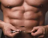 Ein Mann mit starker Muskulatur injiziert sich etwas in den Bauch. Dies könnte mit dem Thema Muskelaufbau Hormone zusammenhängen.