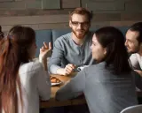 Grupa przyjaciół przy stole. Jedna osoba mówi, gestykulując, choć czuje, że nie umiem rozmawiać z ludźmi.