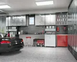 Aménagement garage 15m2 : voiture de sport noire, armoires métalliques, outils, générateur et tabouret rouge.