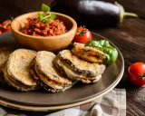 Cotolette di melanzane dorate e croccanti, servite con salsa di pomodoro e basilico fresco.