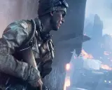 Żołnierz w czapce i goglach, gotowy do akcji w jednej z najbardziej realistycznych gier fps. W tle płonące ruiny i dym.