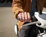 Dłoń trzymająca kierownicę skutera elektrycznego. Może to być związane z dopłatą do skutera elektrycznego.