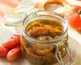 Bocal de tomates séchées à l'huile d'olive, avec des tomates fraîches à côté.