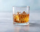 Ein Glas mit bernsteinfarbenem Getränk und Eiswürfeln, das an einen French Connection Cocktail erinnert.