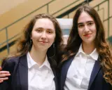Dwie młode kobiety w marynarkach i białych koszulach, uśmiechają się. Czy to początek ich wspólnej drogi? IB co to za przygoda?
