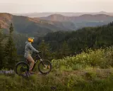Rowerzysta w kasku na tle górskich krajobrazów. Czy koła 27,5 czy 29 cali lepiej sprawdzą się na tej trasie?