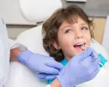 Chłopiec u dentysty, ciekawy, ile zębów ma roczne dziecko. Lekarz bada jego uśmiech.