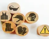 Drewniane krążki z symbolami ochrony: kamizelka, okulary, kask, maska, rękawice, buty i znak ostrzegawczy. Zapobiegają chorobie zawodowej.