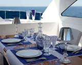 Emplacement des couverts sur une table dressée sur un yacht, avec des verres en cristal, une carafe et des lampes.