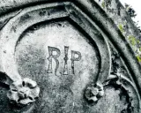 Napis "RIP" na kamiennym pomniku, co oznacza "Requiescat in pace" (Niech spoczywa w pokoju), symbolizuje wieczny odpoczynek.