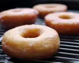 Cuatro donuts glaseados sobre una rejilla, listos para disfrutar. Una deliciosa receta de donuts caseros.