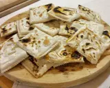 Piatto tipico cesenate: piadina fritta, dorata e leggermente bruciacchiata, servita su un tagliere di legno.