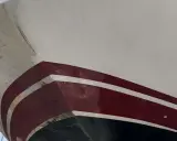 Le carenage d'un voilier blanc et bordeaux, montrant des traces d'usure et de salissures marines.