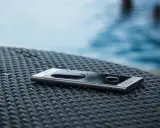 Smartfon z kroplami wody na ekranie, leżący na plecionej powierzchni. Dowód, że ip67 co oznacza: odporność na zanurzenie.