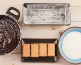 Preparando una deliciosa tarta de galletas y chocolate: chocolate derretido, galletas, molde y leche listos para mezclar.