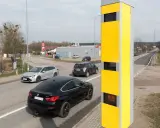 Żółty fotoradar przy drodze, monitorujący ruch samochodów. Tak działa system, który rejestruje prędkość pojazdów.