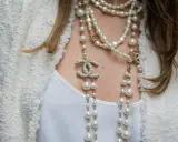 Eleganckie stylizacje z perłami, w tym wielowarstwowy naszyjnik Chanel z logo marki i perłami, dodają blasku białej bluzce i żakietowi.