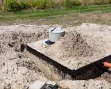 Budowa szamba: betonowa konstrukcja z rurą wylotową, przygotowana do uszczelnienia.