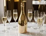Une bouteille de champagne dorée est entourée de flûtes remplies de bulles. Combien de coupe dans une bouteille de champagne ? La fête commence !