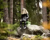 En mystisk staty med gyllene tyg över huvudet sitter på en sten i **stadsparken Falun**.