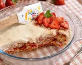 Un délicieux tiramisu fraise, garni de fruits frais et d'une touche de cacao, prêt à être dégusté.