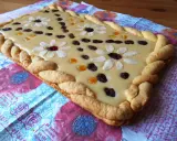Pyszny mazurek z mlekiem w proszku, ozdobiony płatkami migdałów, rodzynkami i kandyzowanymi owocami, z warkoczowym brzegiem.