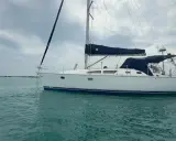 Voilier blanc à l'ancre, voiles bleues repliées. Un avis sur le Sun Odyssey 37, prêt pour l'aventure.