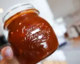 En hand håller ett glas med en mörkröd rabarberchutney. Texten "Quartier" är präglad på glaset.