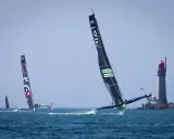 Le trimaran Koesio fend les vagues, une course intense près d'un phare.