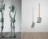 Two abstract bronze figures stand side-by-side, a modern sculpture. To the right, a metal snow shovel hangs suspended, its shadow cast on the wall.