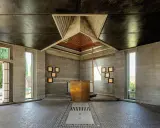 Interno moderno con altare dorato, pareti in cemento grezzo e soffitto a punta. Un esempio di architetti famosi italiani.
