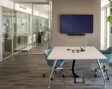 Un bureau futuriste avec une table de réunion, des chaises bleues, un écran mural et des cloisons vitrées.