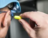 Obrero se prepara para el ruido con un epi para ruido amarillo.