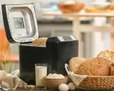 Machine à pain ouverte, avec du pain frais dans un panier. Avis sur la machine à pain : facile et pratique pour un pain maison.