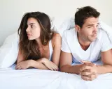 Para jak rozładować napięcie seksualne, leży pod kołdrą. Kobieta patrzy w bok, mężczyzna w przeciwnym kierunku.