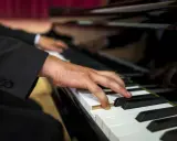 Dłoń muzyka w garniturze gra na fortepianie. Zastanawiasz się, ile bierze organista za ślub?