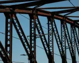 Estructura de puentes de hierro famosos contra el cielo azul. Cables cruzan la intrincada red de vigas oxidadas.
