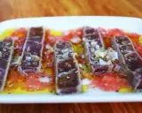 Tiras de atún marinado sobre rodajas de tomate y cítricos, un delicioso plato de comida típica de Huelva.