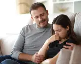 Un homme réconforte une femme en pleurs, son regard suggère une manipulation subtile, un exemple de pervers narcissique.