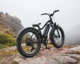 Czarny rower elektryczny na skalistym, mglistym tle. To dowód na to, że polski producent rowerów elektrycznych tworzy sprzęt gotowy na każdą przygodę.