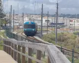Ein Zug fährt auf den Gleisen in Richtung einer Marina mit vielen Segelbooten. Die Fahrt von Lissabon in die Algarve ist ein Erlebnis.