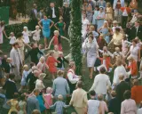 Många barn och vuxna dansar ringdans runt en midsommarstång i Sverige.