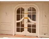 Eleganckie drzwi dwuskrzydłowe z łukiem i ozdobną sztukaterią. Planowanie sztukaterii wokół drzwi podkreśla ich styl.