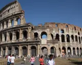 Le Colisée de Rome avant sa restauration complète, avec des touristes admirant son architecture antique sous un ciel bleu.